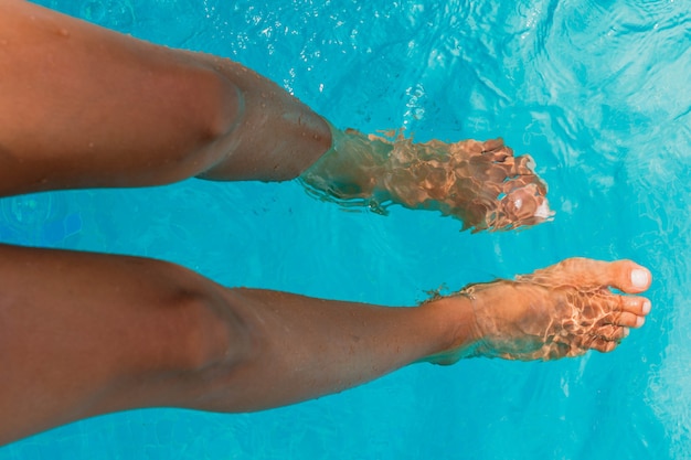 legs of tanned woman in swimming pool