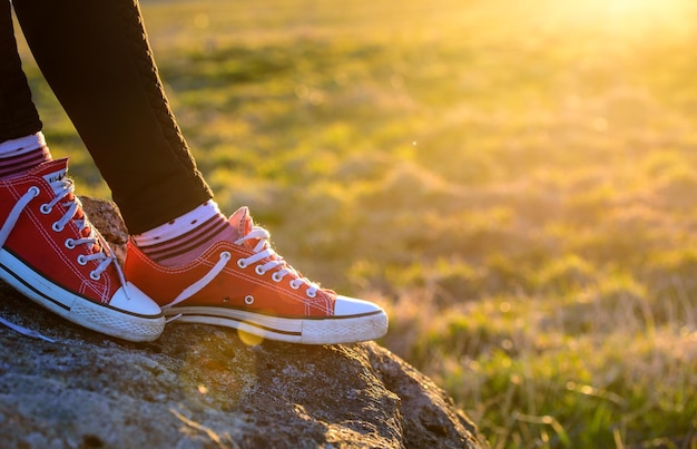 Legs of a tourist in red sneakers against the sunset