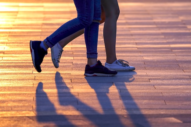 햇빛을 배경으로 걷는 두 사람의 다리. 우정과 관계의 동기화