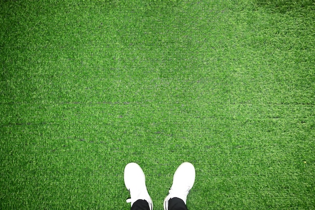 Legs of unrecognizable father and son standing against artificial grass Studio shot on green background