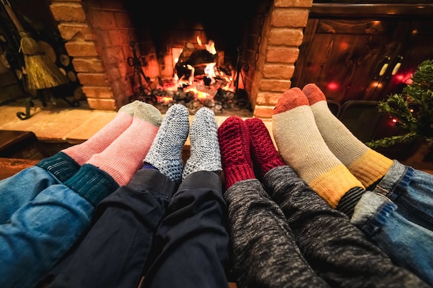 Legs view of happy family wearing warm socks in front of cozy fireplace - Focus on left socks