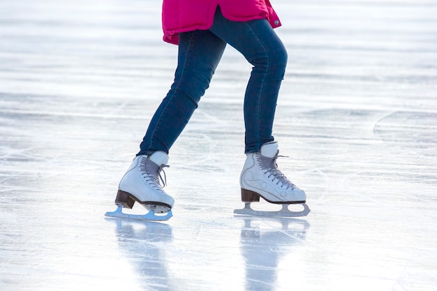 Legs of a woman in blue jeans and white skates on an ice rink. hobbies and leisure. winter sports