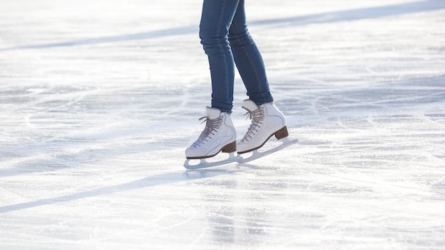 Legs of a woman in blue jeans and white skates on an ice rink. hobbies and leisure. winter sports