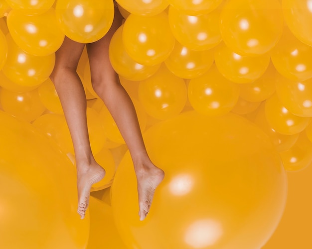 Foto gambe di donna tra molti palloncini gialli