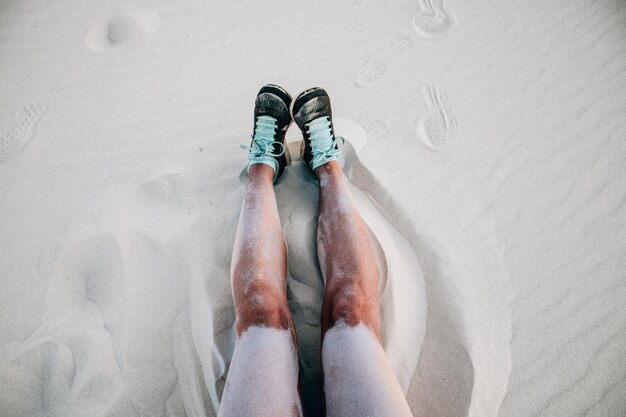 Photo legs of a woman sitting on sand