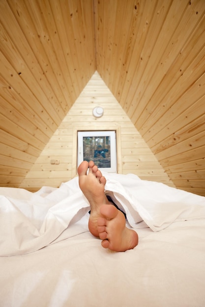 Legs of woman stick out from under cosy blanket