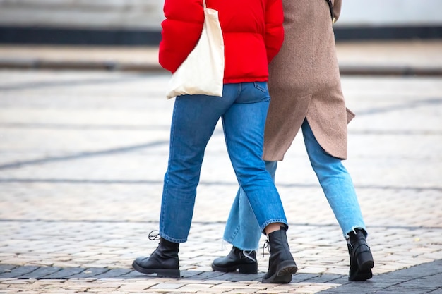 街の通りを一緒に歩くジーンズの女性の足