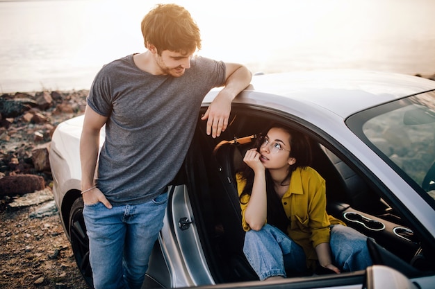 Legs of a young girl in white boots in a car window on a background of the coast of the sea, flat lay. Enjoyment, relaxation in the tourism, travel, free time, rest, the concept of happiness.