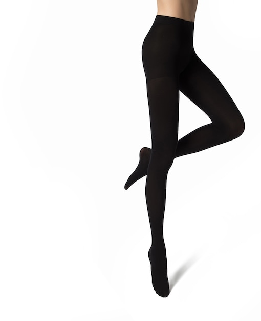 Legs of a young woman in black nylon tights on white background