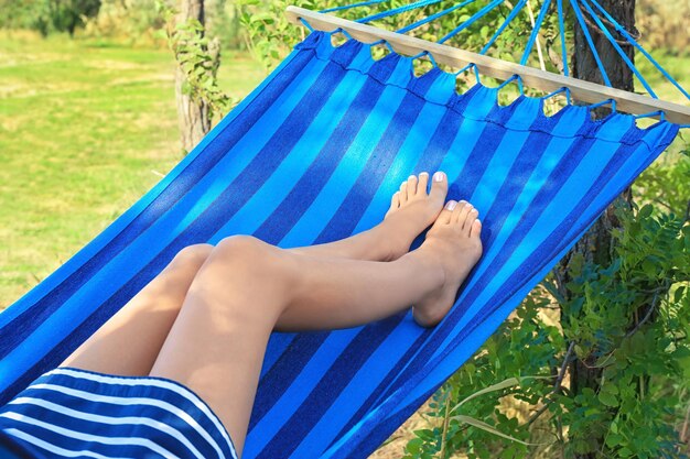 Legs of young woman relaxing in hammock outdoors