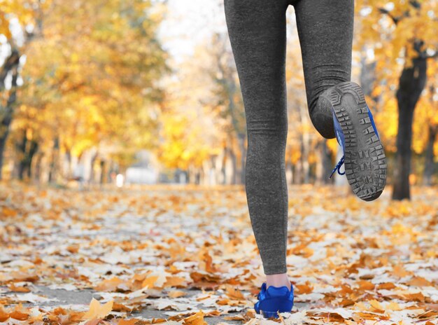 Legs of young woman running in autumn park