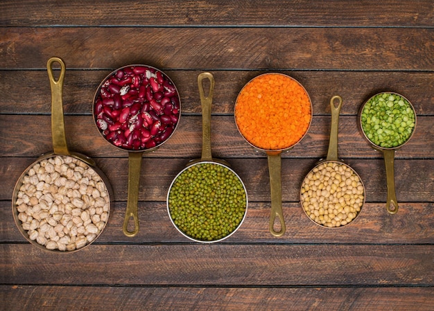 Legumes set in vintage scoops on wooden background