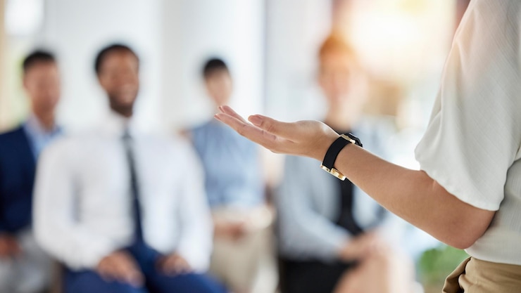 Foto leiderschapspresentatie en handen van een manager in een conferentie voor een vergadering of trainingsworkshop coachend personeel en een spreker met een toespraak praten en staan met werknemers voor een seminar