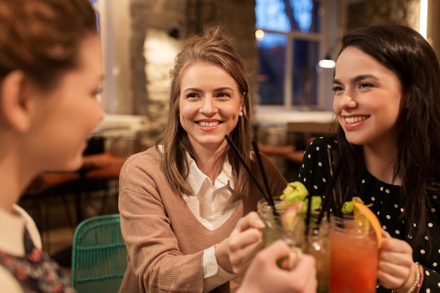 концепция отдыха, праздника, вечеринки, людей и праздников - счастливые друзья звенят напитками в ресторане
