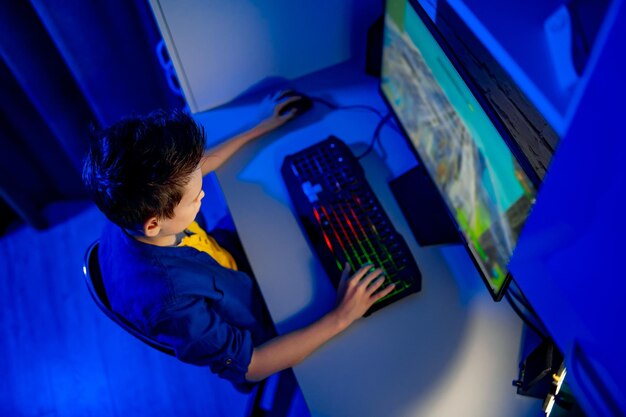 Leisure children technology and people concept gamer boy with at computer playing video game at home