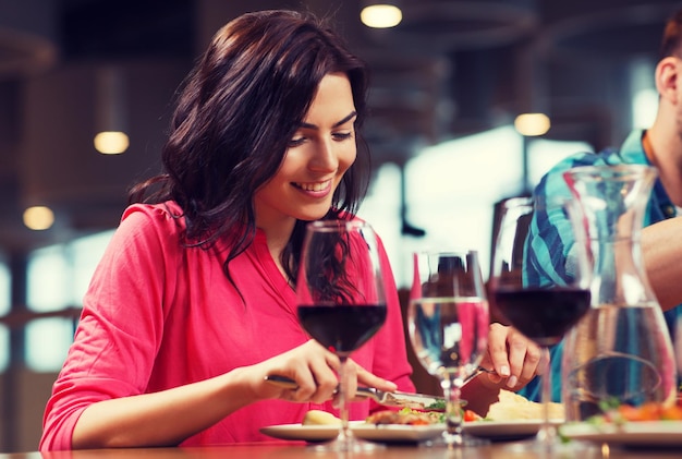 leisure, food and drinks, people and holidays concept - happy woman with friends having dinner at restaurant