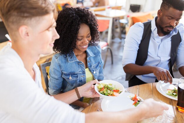 Photo leisure, food and people concept - group of happy international friends eating and talking at restaurant table