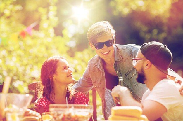 Foto tempo libero, vacanze, comunicazione, persone e concetto - amici felici a cena alla festa estiva in giardino