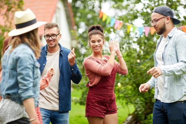 leisure, holidays, fun and people concept - happy friends dancing at summer party in garden