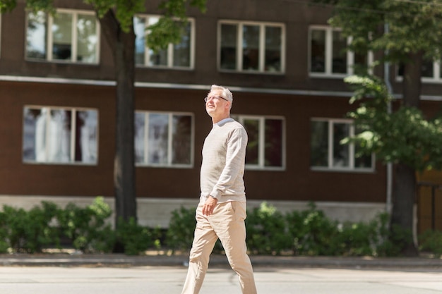 leisure and people concept - senior man walking along summer city street