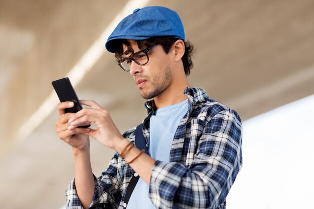 leisure, technology, communication and people concept - hipster man texting message on smartphone or playing augmented reality game