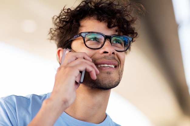 leisure, technology, communication and people concept - man in eyeglasses calling on smartphone on street