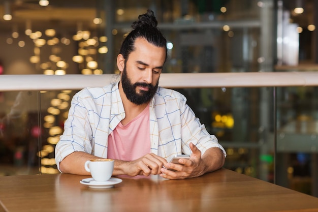 leisure, technology, lifestyle and people concept - man with smartphone and coffee at restaurant