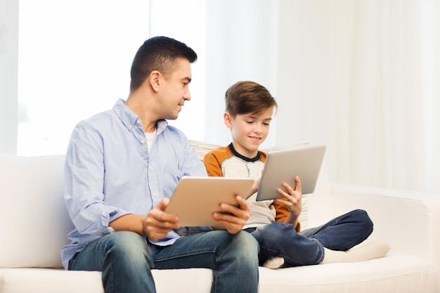 leisure, technology, technology, family and people concept - happy father and son with tablet pc computer networking or playing at home