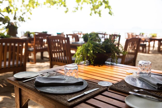 leisure, travel and tourism concept - served table at open-air restaurant on beach