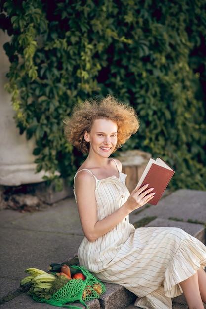 Leisure. Young woman sitting on the steps with a book in hands