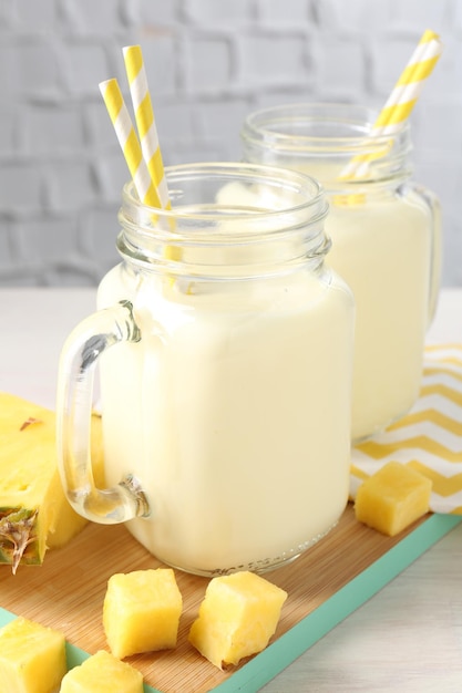Lekker ananas smoothie in potten en vers fruit op tafel.