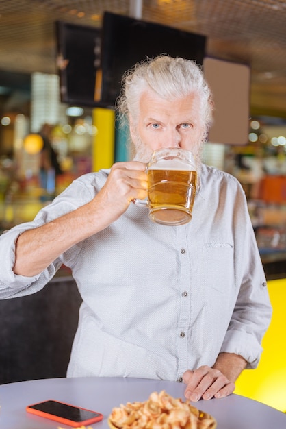 Lekker bier. blij, vrolijke man die alcohol drinkt tijdens het rusten in de kroeg