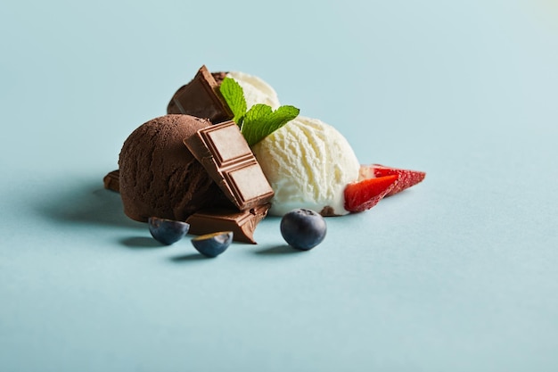 Lekker bruin en wit ijs met bessen, chocolade en munt op blauwe achtergrond