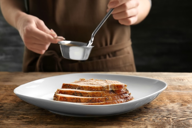 Lekker gesneden kalkoen op bord en chef-kok met jus in kleine steelpan aan tafel