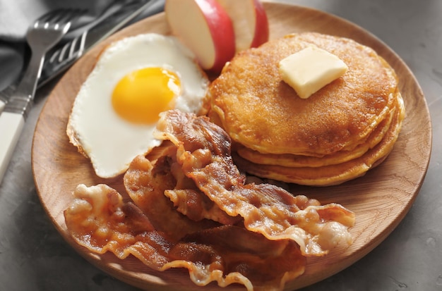 Lekker ontbijt met gebakken eierpannenkoekjes en spek op een houten bord