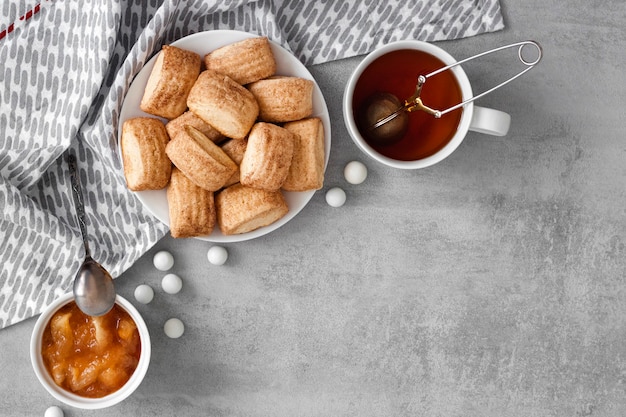 Lekker ontbijt. Zelfgemaakte zoete kaneelkoekjes, kopje thee en appelconfituur. Flatlay, bovenaanzicht, kopieerruimte