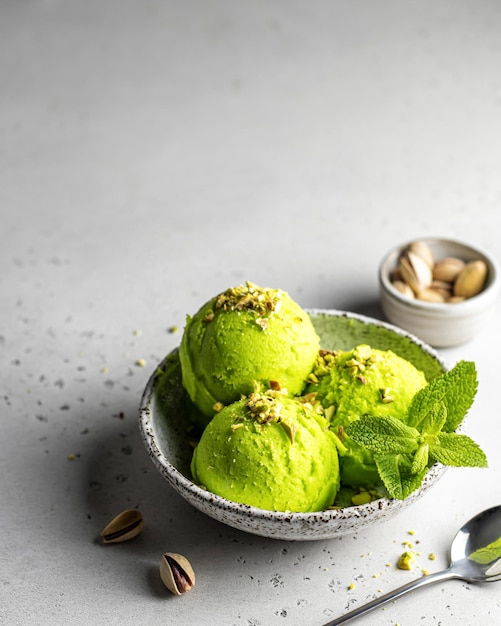 Lekker pistache-ijs met munt gegarneerd met gemalen pistachenoten op gestructureerde achtergrond