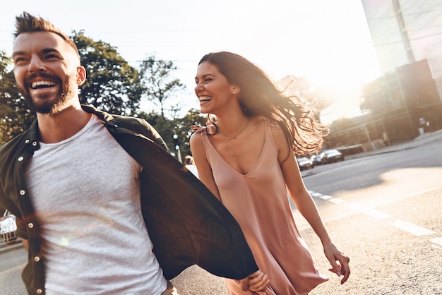 Lekker samen wandelen. Mooie jonge paar hand in hand en glimlachen tijdens het wandelen door de stad straat