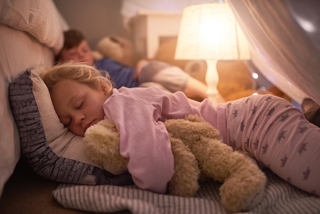 Lekker slapen met zoete dromen Bijgesneden opname van broers en zussen die thuis onder een dekenfort slapen