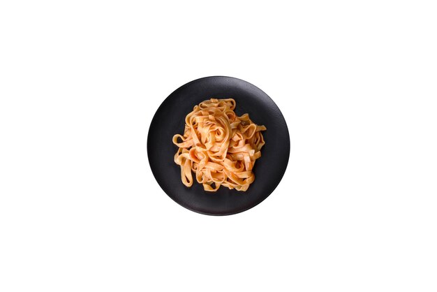 Lekker smakelijk pasta tagliatelle spaghetti met tomatensaus en parmezaanse kaas geserveerd op een zwarte plaat op een donkere betonnen tafel