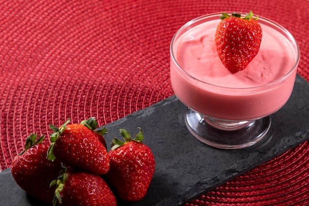 Lekkere aardbeienmousse in glas met aardbei erop.