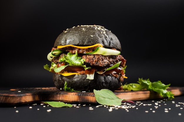 Lekkere ambachtelijke burger met zwart broodje op de zwarte achtergrond