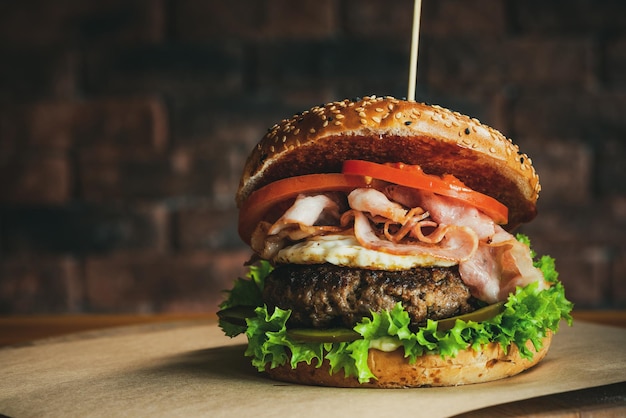 Foto lekkere amerikaanse burger met bacon rundvlees en ei op houten tafel bakstenen muur copyspace achtergrond