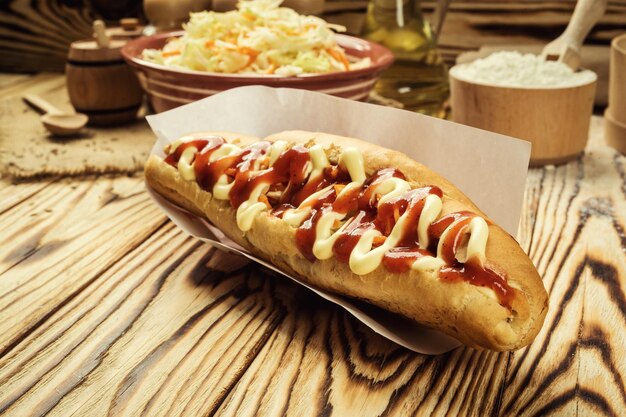 Lekkere barbecue gegrilde hotdog met saus en gele mosterd-pickles en Franse frietjes op houten achtergrond close-up