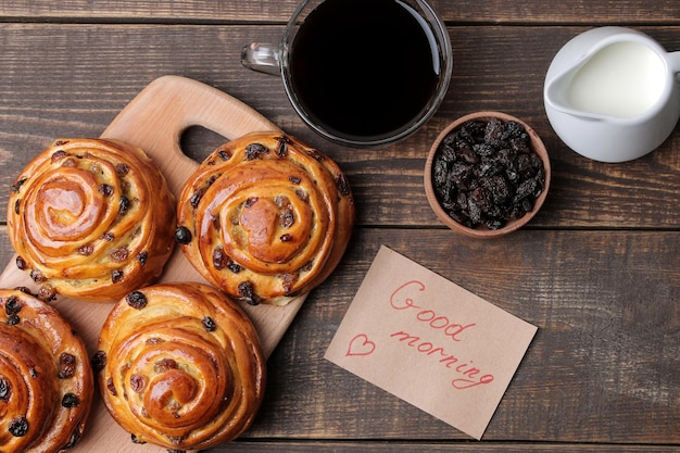 Lekkere broodjes met rozijnen en koffie met melk op een bruine houten achtergrond verse bakkerij ontbijt weergave van bovenaf