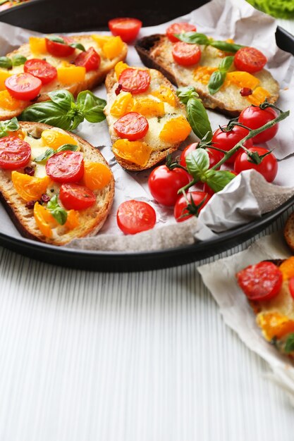 Lekkere bruschetta met tomaten in pan, op tafel