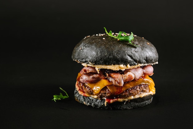 Lekkere burger met zwart broodje op een zwarte achtergrond