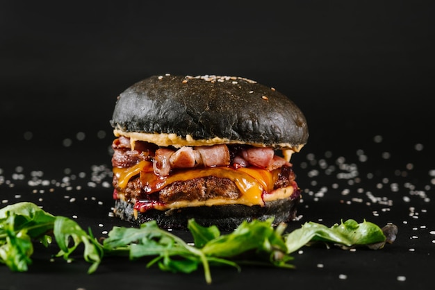 Lekkere burger met zwart broodje op een zwarte achtergrond