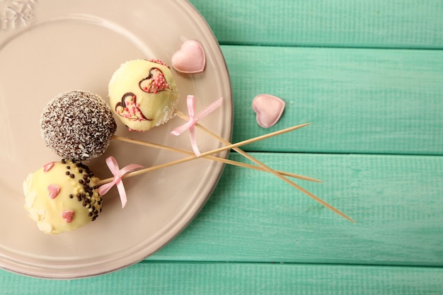 Lekkere cake pops op bord, op houten tafel