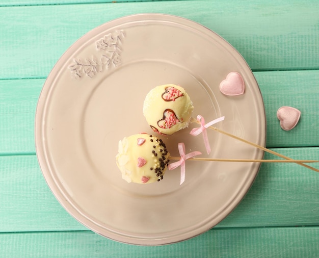 Lekkere cake pops op bord, op houten tafel